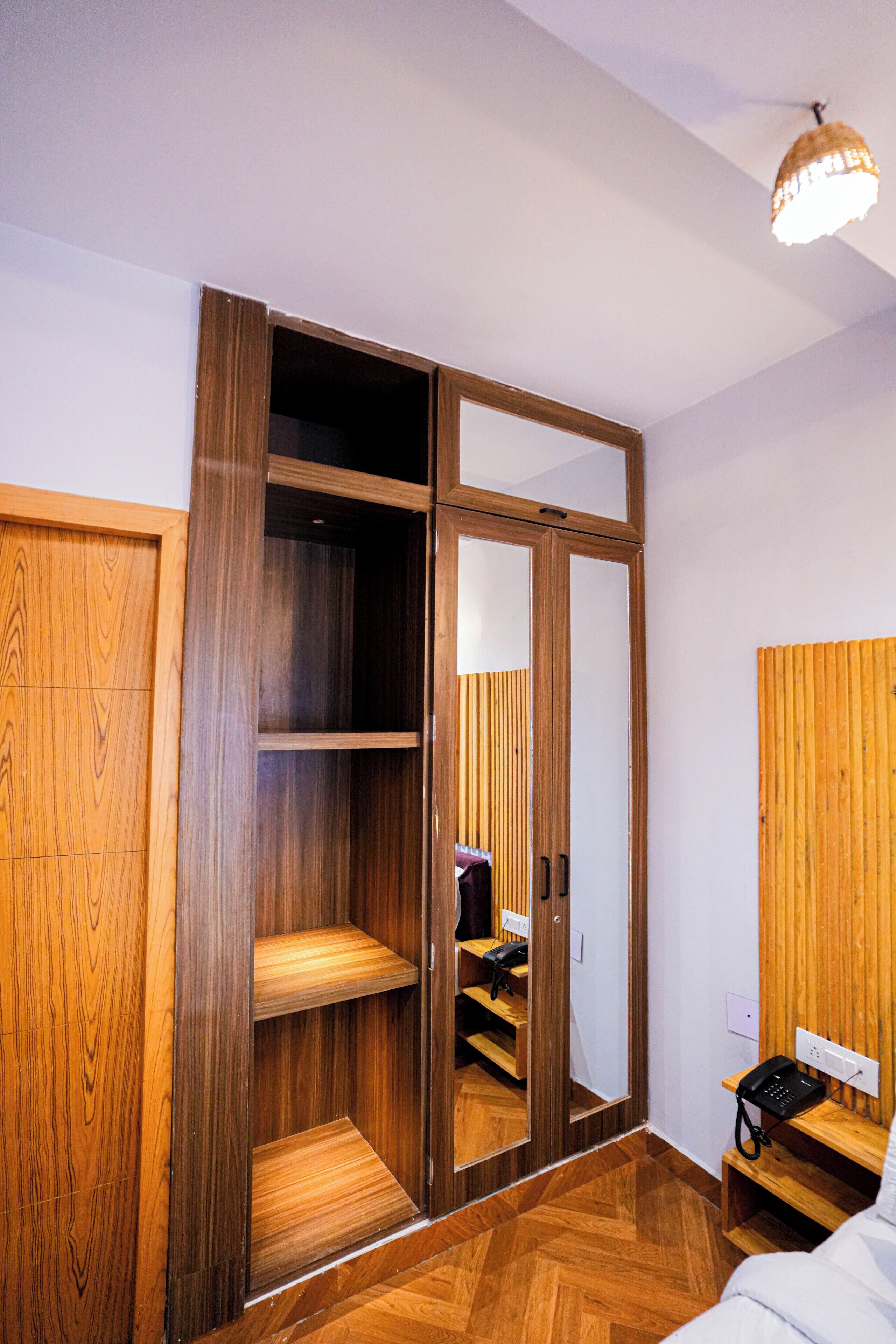 Quarto com guarda-roupa de madeira, espelho e telefone.