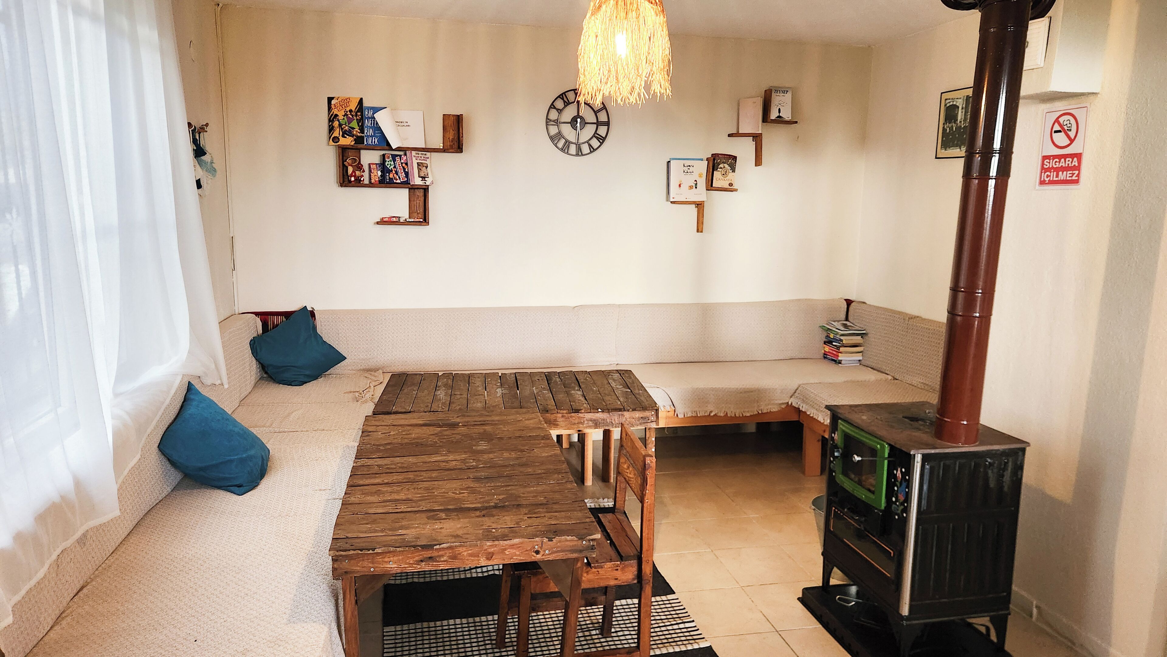 A cozy living room with a wooden table, a sofa, a clock, and a fireplace.
