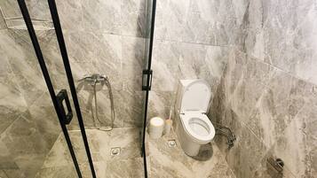 Un baño con inodoro, ducha e inodoro de lavado.
