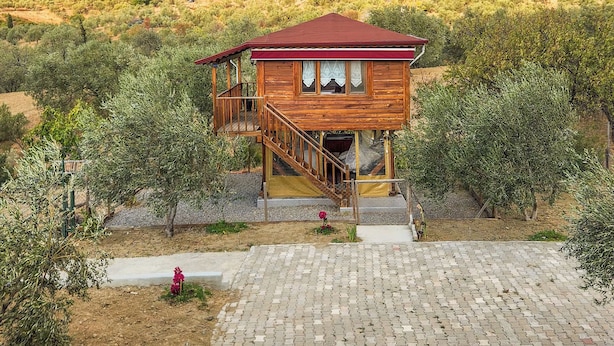 Una cabaña de madera con techo rojo, un balcón y una mesa con sillas al frente.