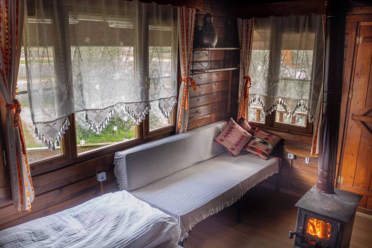 A cozy cabin room with a wooden bench, a small table, and a fireplace.