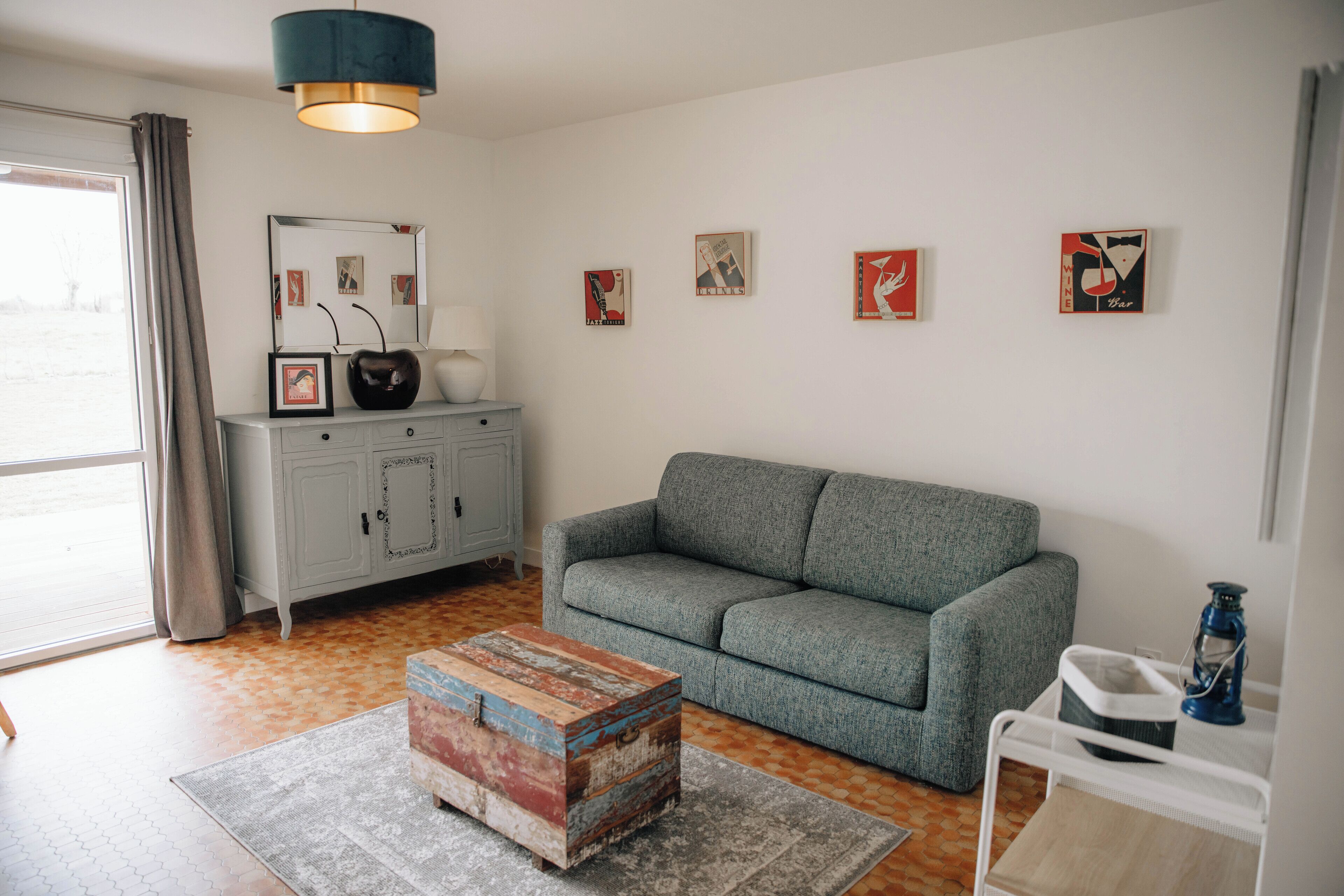 Un salon avec un canapé gris, une table basse en bois, un meuble et des œuvres d’art murales.