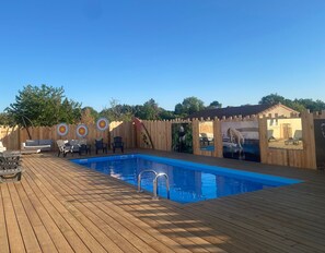 A wooden deck with a swimming pool, lounge chairs, and a wooden fence with animal murals.