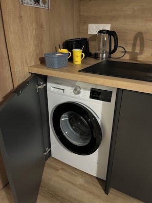 A compact kitchen with a Siemens washing machine, a coffee maker, and a small countertop.