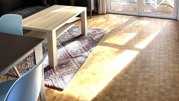 Un salon comprenant un canapé, une table basse, une lampe, un meuble et une grande fenêtre donnant sur un paysage verdoyant.