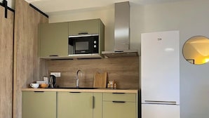 Une cuisine moderne avec des meubles de couleur verte, un four à micro-ondes, un évier et un réfrigérateur blanc.