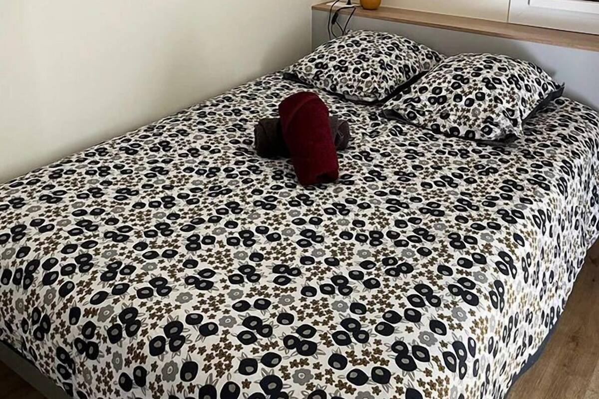A bedroom with a bed, a nightstand, and a lamp. There are three framed pictures on the wall.