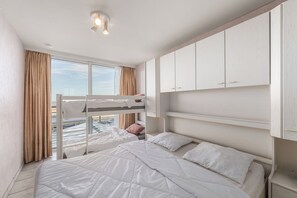 A bedroom with bunk beds, a window with curtains, and a ceiling light. - 1 bedroom accommodation in Blankenberge (Blankenberge)