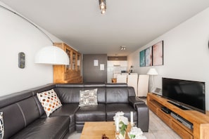 Ein modernes Wohnzimmer mit einer Ledersofa, einem Flachbildfernseher und einem Holztisch.