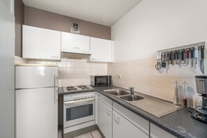Eine moderne Küche mit weißen Schränken, einem Backofen, einer Mikrowelle und einer Kaffeemaschine.