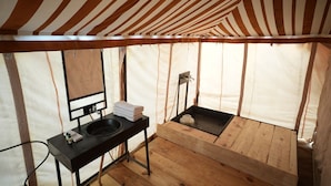 A tent-style room with a wooden floor, a black sink, and a mirror. - Van Bagh Camp Village (Alwar)