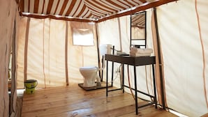 A tent with a striped ceiling, a toilet, a sink, and a small table with a towel. - Van Bagh Camp Village (Alwar)