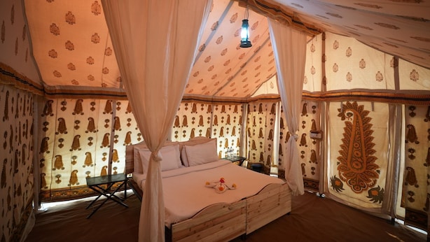 A tent-style room with a bed, curtains, and patterned walls. - Van Bagh Camp Village (Alwar)