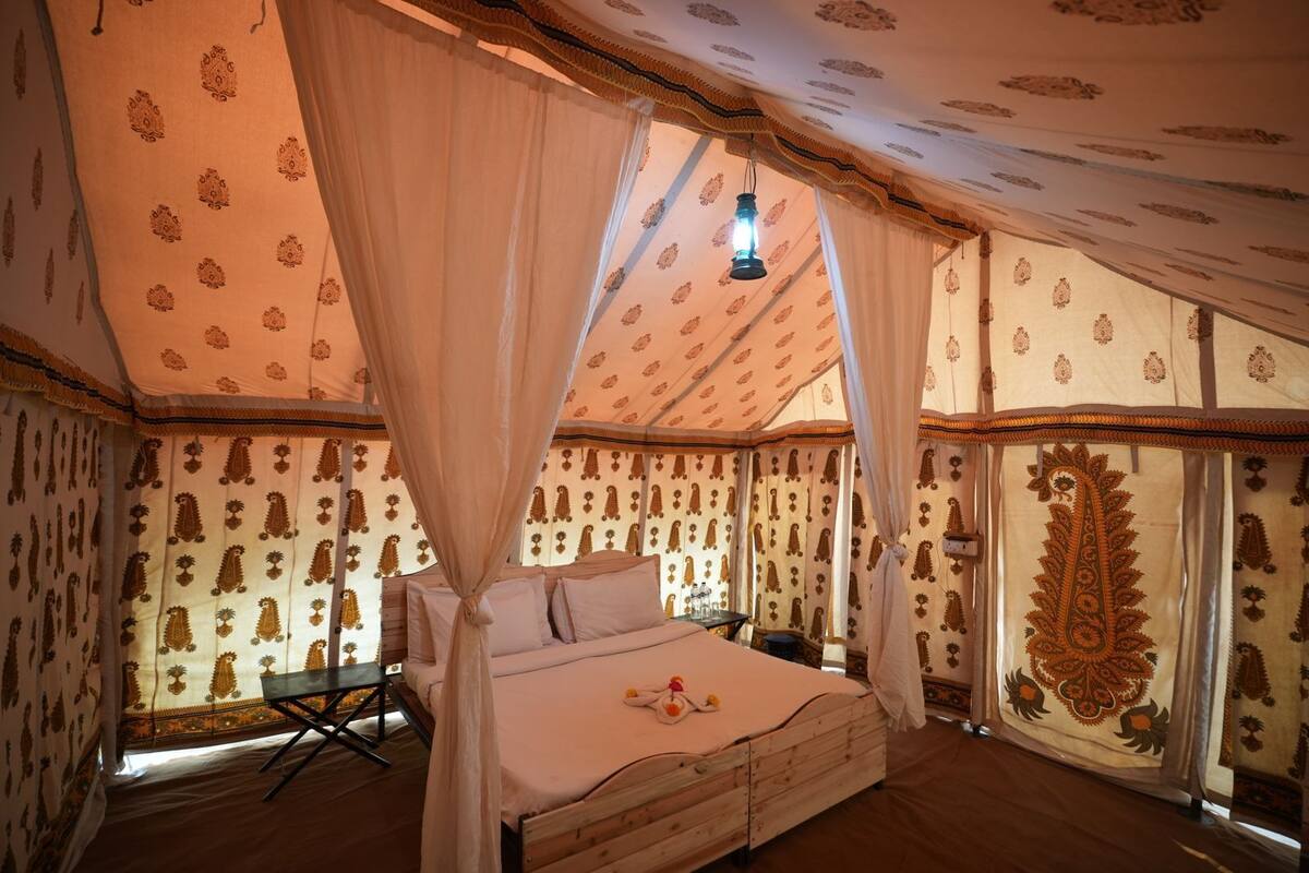 A tent-style room with a bed, curtains, and patterned walls.