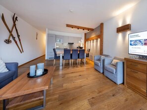 A modern living room with a wooden coffee table, a sofa, and a TV screen displaying a webpage.