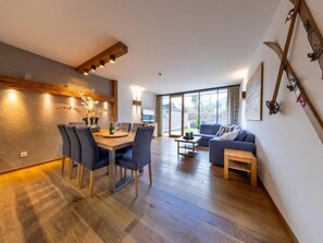 Een moderne woonkamer met een eethoek, grote ramen en een open haard.