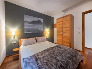 Un dormitorio con una cama, un armario de madera, una lámpara de pared e imagen enmarcada.