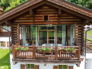 Eine Holzchalet mit Balkon, großen Fenstern und Sitzgelegenheit im Freien.