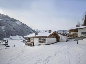 Schneebedeckte Berglandschaft mit einer Holzhütte und einem größeren Gebäude mit Balkon.