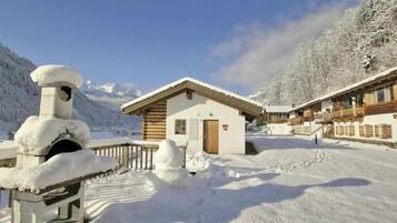 Ein mit Schnee bedecktes Berghotel mit Holzfassade und einem zentralen Gebäude mit einer braunen Tür.