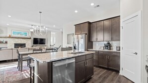 A modern kitchen with dark wood cabinets, stainless steel appliances, and a central island with a dishwasher.