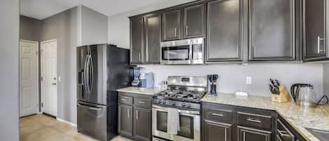 A kitchen with dark cabinets, stainless steel appliances, a microwave, and a gas stove.