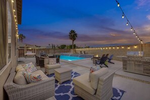 An outdoor pool area with lounge chairs, a hot tub, and a barbecue grill.