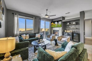 A modern living room with a sofa, chairs, a coffee table, and a fireplace. - Wonders Nest: Pool, Spa, Arcades, Putting Green! (Coachella)