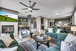 Un salon moderne avec une cheminée, deux canapés, une table basse et une cuisine en arrière-plan.