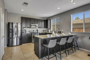 A modern kitchen with dark cabinetry, stainless steel appliances, and a central island with bar stools.