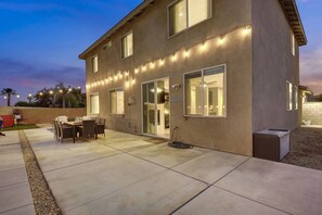 A two-story house with a patio, outdoor seating, and string lights.