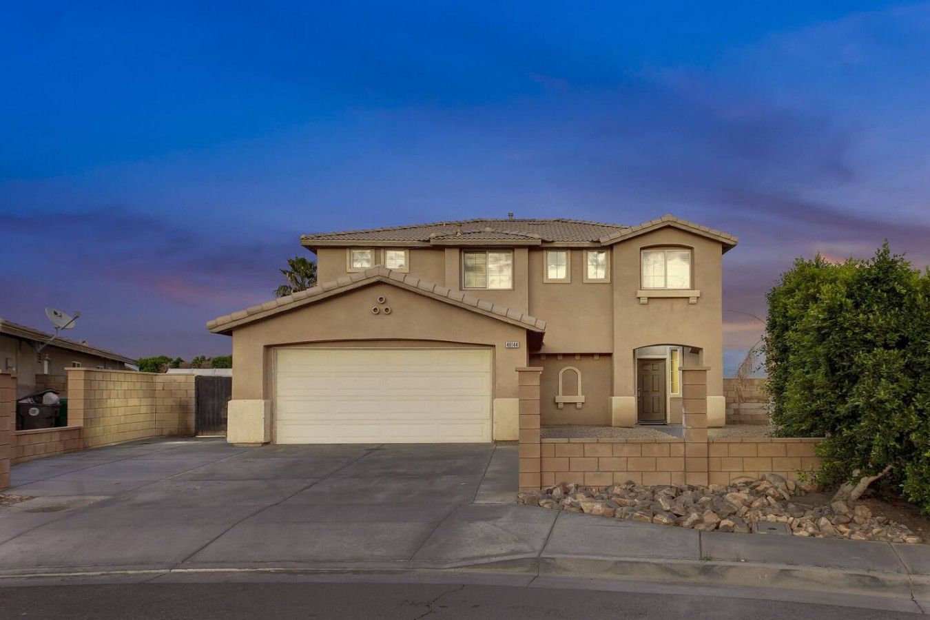 A two-story house with a garage, a small porch, and a well-maintained lawn.