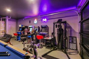 A home gym with exercise equipment, arcade games, and a ping pong table. - Wonders Nest: Pool, Spa, Arcades, Putting Green! (Coachella)