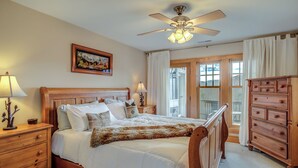 A bedroom with a wooden bed, a nightstand, a dresser, and a ceiling fan.