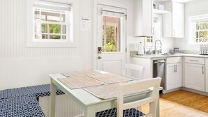 A room with a dining table, chairs, a kitchen area with cabinets and a sink, and a window with blinds. - Charming Folly Beach Home - Perfect Location (Folly Beach)