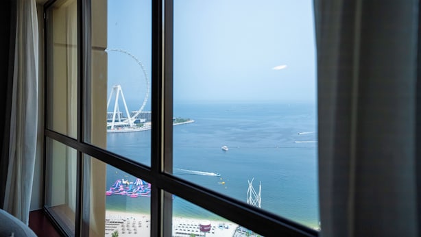 A view of a coastal area with a bridge and ferris wheel in the distance. - YouSleep Hostel (Dubai)