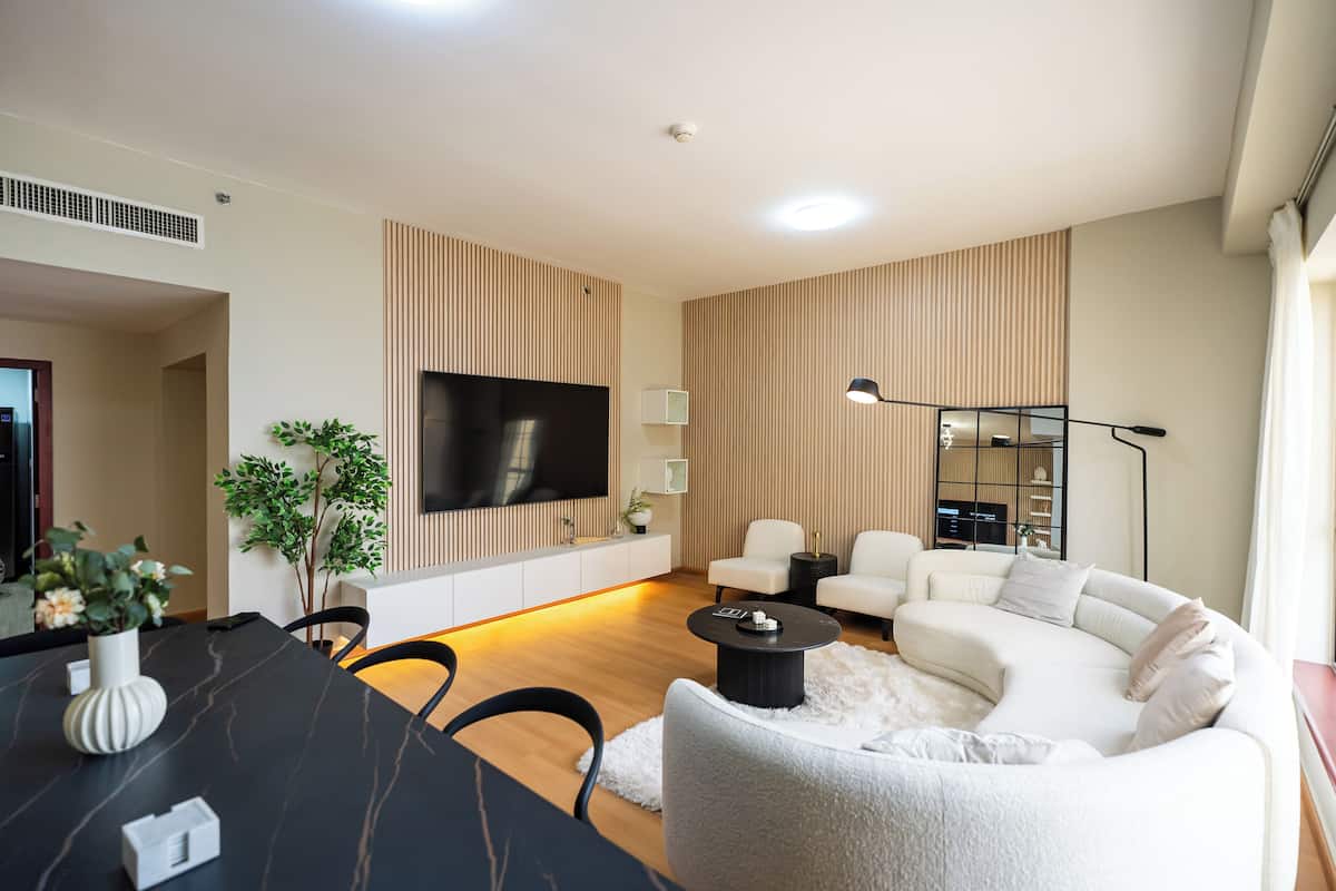 A modern living room with a flat-screen TV, a dining table, and a sofa.
