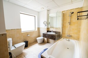 A modern bathroom with a bathtub, toilet, bidet, and sink. - YouSleep Hostel (Dubai)