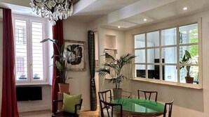 A dining area with a round table, chairs, and a chandelier. - Testaccio GreenHouse | ArtDesignApartments (Rome)
