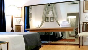 A hotel room with a bed, a mirror, a chair, and a red rug. - Testaccio GreenHouse | ArtDesignApartments (Rome)