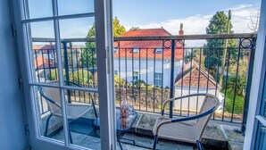 Een balkon met twee stoelen, een tafel en een fles wijn.