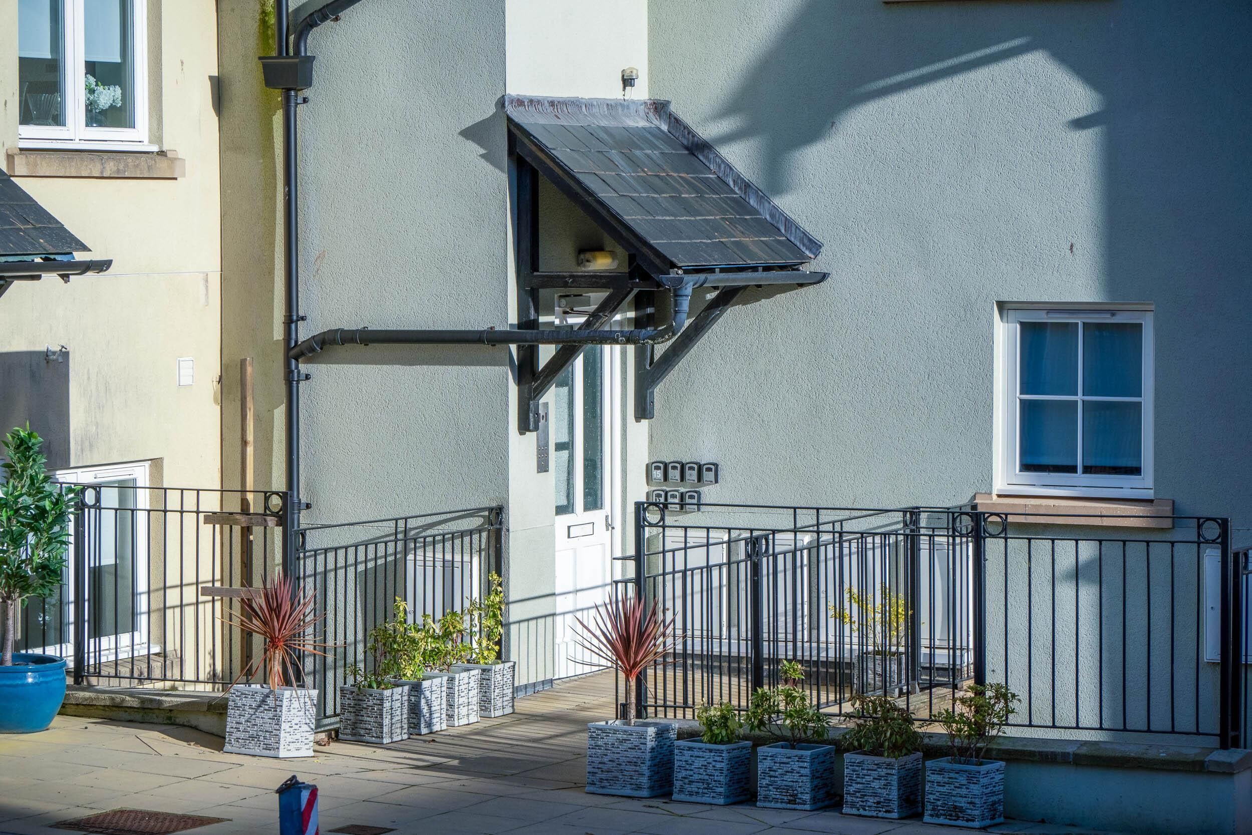 A building with a solar panel, a gated entrance, and potted plants.