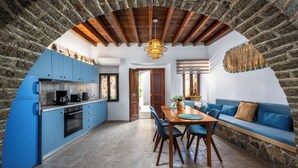 Une cuisine avec des meubles de rangement bleus, une table à manger avec des chaises et un mur en pierre.