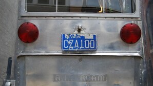 Un autobus avec une plaque d’immatriculation bleue portant l’inscription « CZA100 » et le mot « EVADA » à l’arrière.