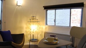 Une pièce de taille modeste, avec une petite table et des chaises, une fenêtre donnant sur un paysage agréable et un luminaire fixé au mur.
