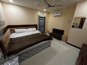 Un dormitorio con cama, sofá, ventilador de techo, aire acondicionado y piso de baldosas.