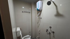 A small, tiled bathroom with a toilet, bidet, and shower. - Hotel Shree Parwati Palace (Ujjain)
