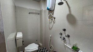 A small, compact bathroom with a toilet, a shower, and a sink. - Hotel Shree Parwati Palace (Ujjain)