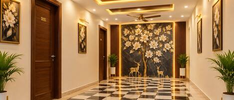 A hotel lobby with a checkered floor, wooden doors, and wall-mounted artwork.