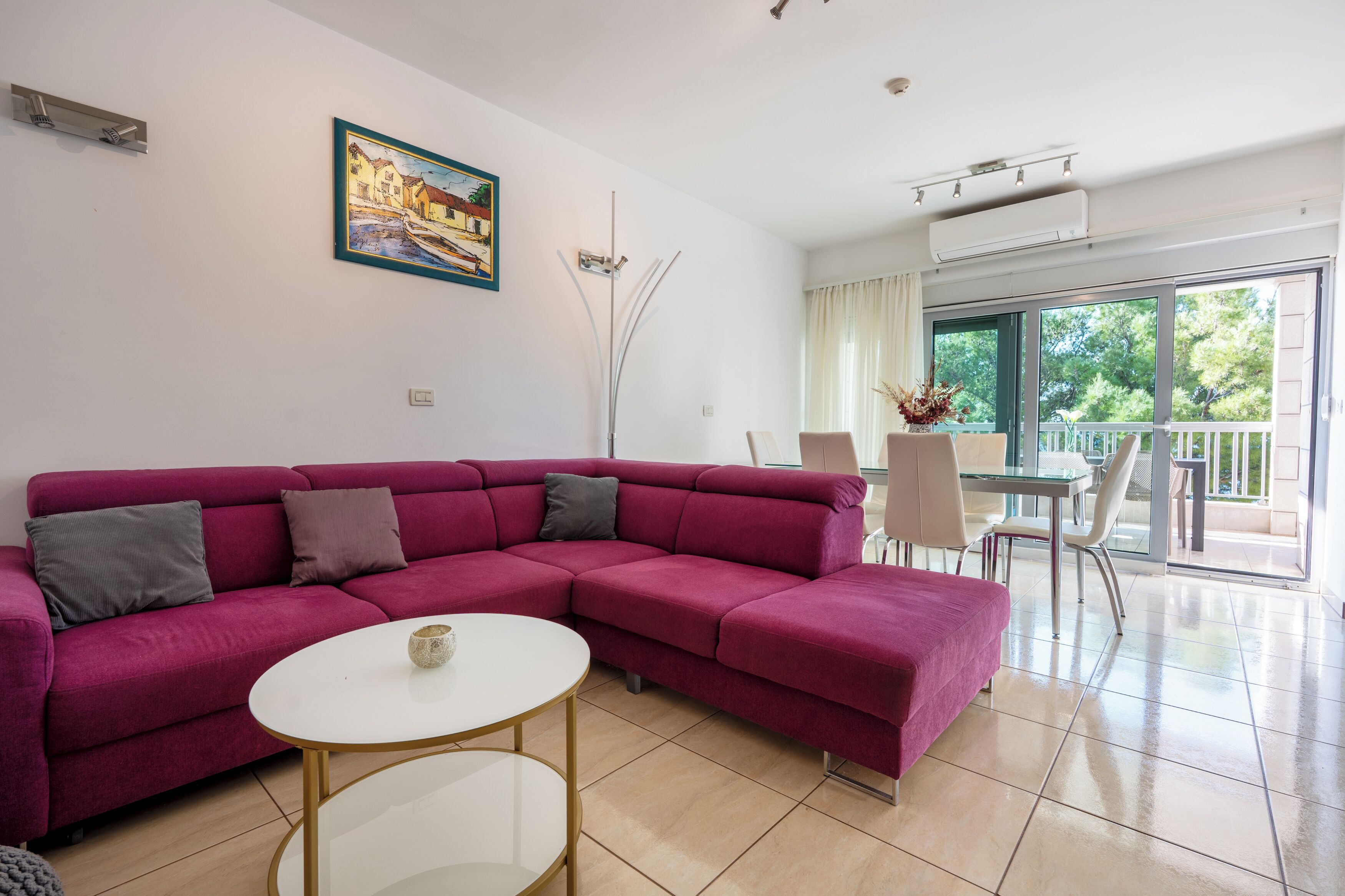 A living room with a sectional sofa, a round coffee table, and a dining area with a table and chairs.
